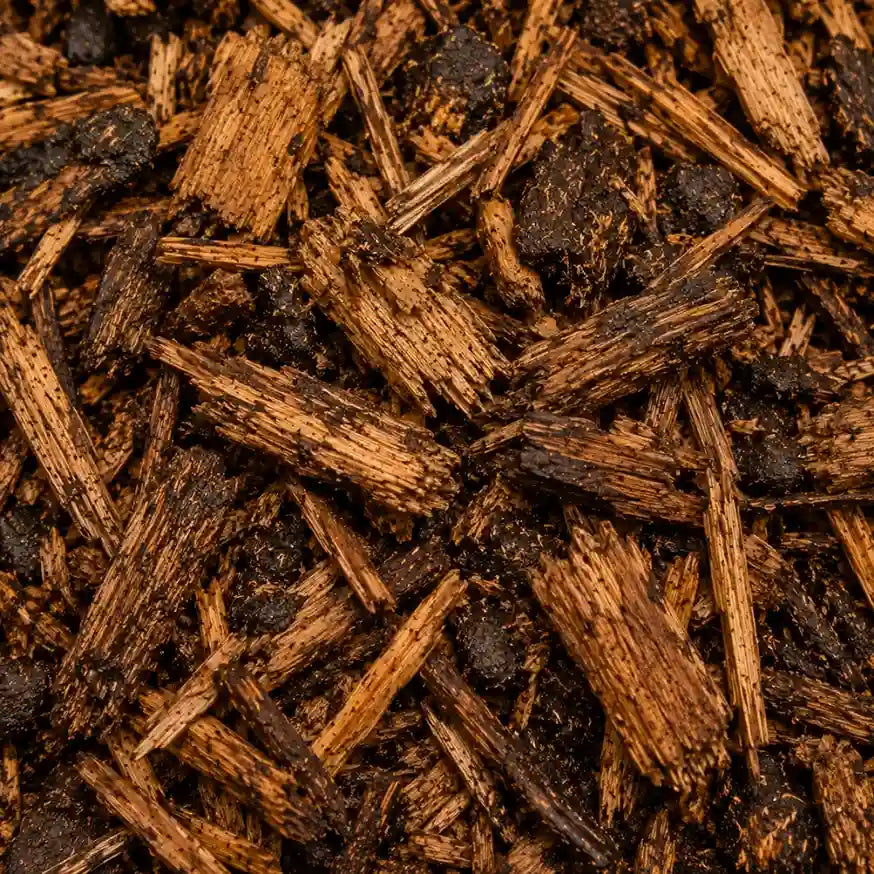 Close-up of shredded brown wood mulch or bark chips with varying shades from light tan to very dark brown.