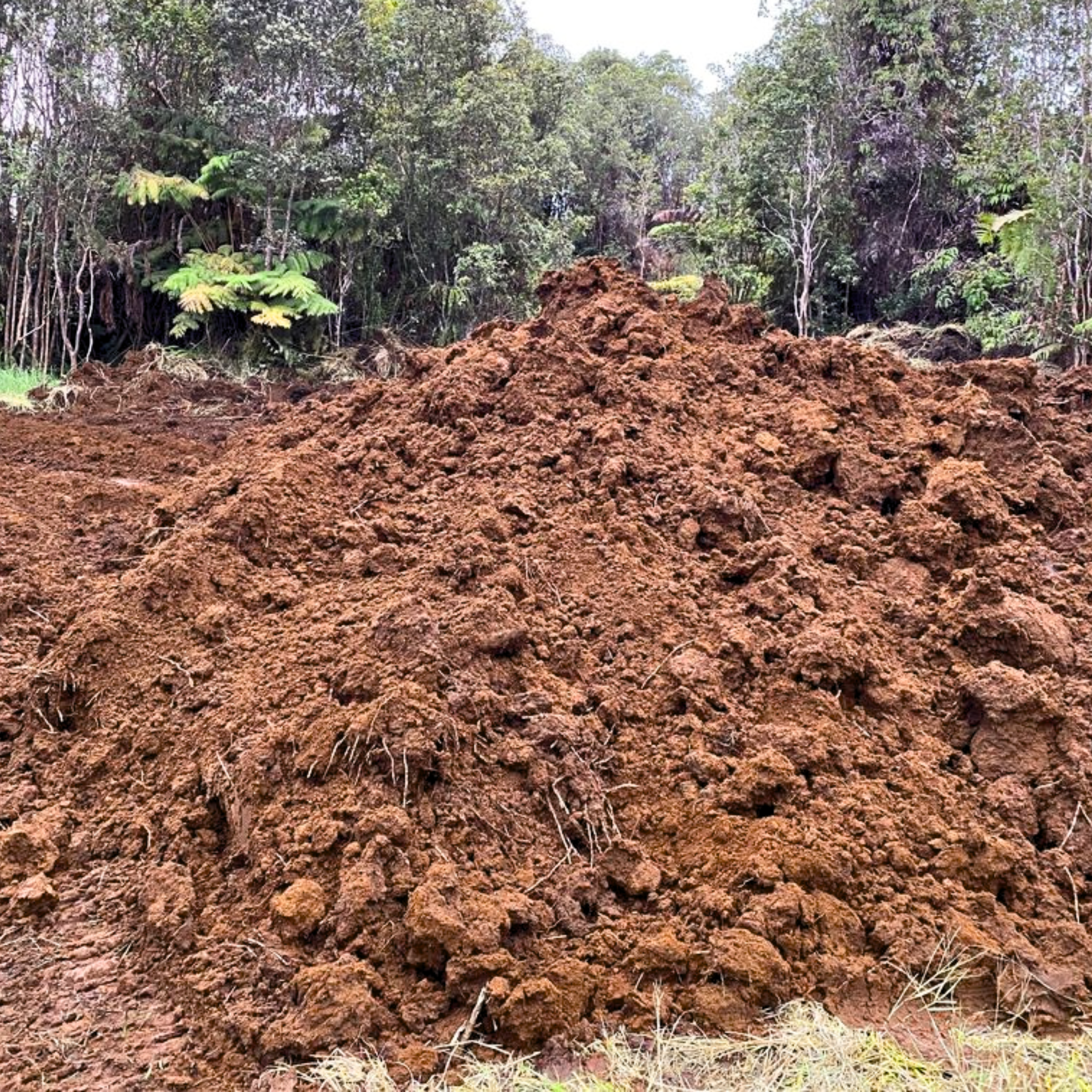 A pile of brown organic top soil, mix of nutrient-rich soil and red cinder, for gardening.